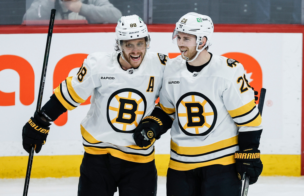 Boston Bruins' David Pastrnak (88) and Elias Lindholm (28) celebrate Lindholm's goal against the Winnipeg Jets during the third period of an NHL hockey game, in Winnipeg, Manitoba, Thursday, Dec. 11, 2025. (John Woods/The Canadian Press via AP)