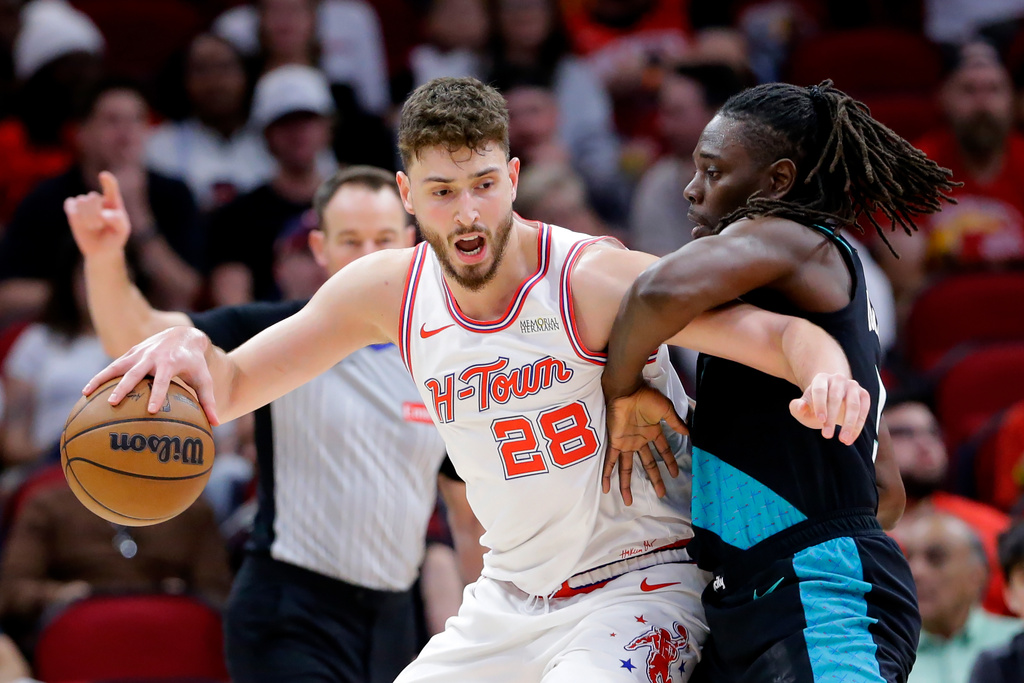 Houston Rockets center Alperen Sengun (28) drives into Portland Trail Blazers guard Jrue Holiday, right, during the first half of an NBA basketball game Friday March 6, 2026, in Houston. (AP Photo/Michael Wyke)