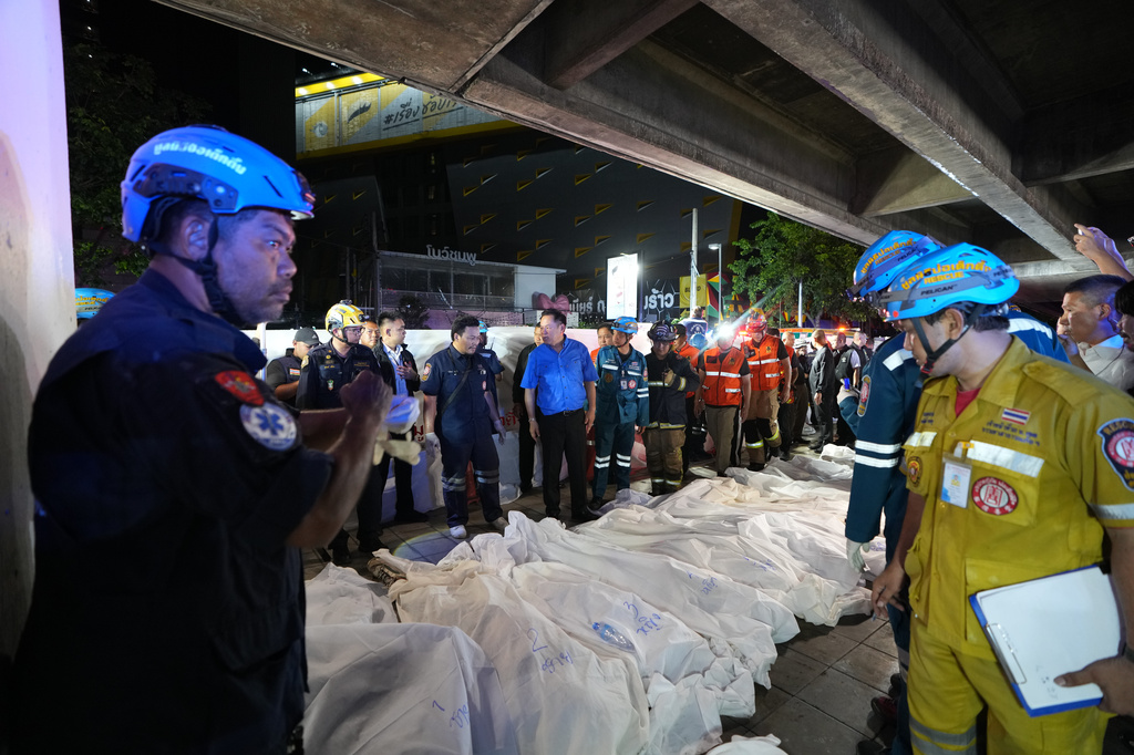 Thailand Prime Minister Anutin Charnvirakul, in blue, inspects the site of a fire as bodies of victims are laid in a row in Bangkok, Thailand, Monday, July 13, 2026. (AP Photo/Sakchai Lalit)