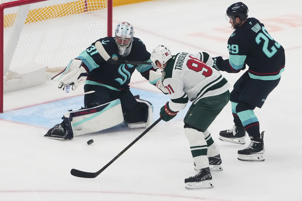 Seattle Kraken goaltender Philipp Grubauer (31) fends off a shot from Minnesota Wild right wing Vladimir Tarasenko (91) as Kraken defenseman Vince Dunn (29) looks on during the first period of an NHL hockey game Thursday, Jan. 8, 2026, in Seattle. (AP Photo/Lindsey Wasson)