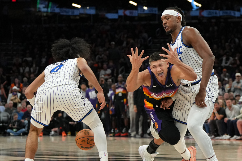 Phoenix Suns guard Grayson Allen reacts after loosing the ball in between Orlando Magic guard Anthony Black (0) and center Wendell Carter Jr. during the second half of an NBA basketball game, Saturday, Feb. 21, 2026, in Phoenix. (AP Photo/Rick Scuteri)