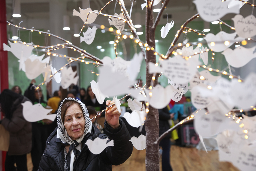 People post handwritten messages on a tree, part of a dedicated memorial space for the lives lost in Iran, during the Pomexpo Norooz Bazaar in New York, on Saturday, March 14, 2026, for the upcoming Nowruz, Iranian/Persian New Year's day. (AP Photo/Heather Khalifa)