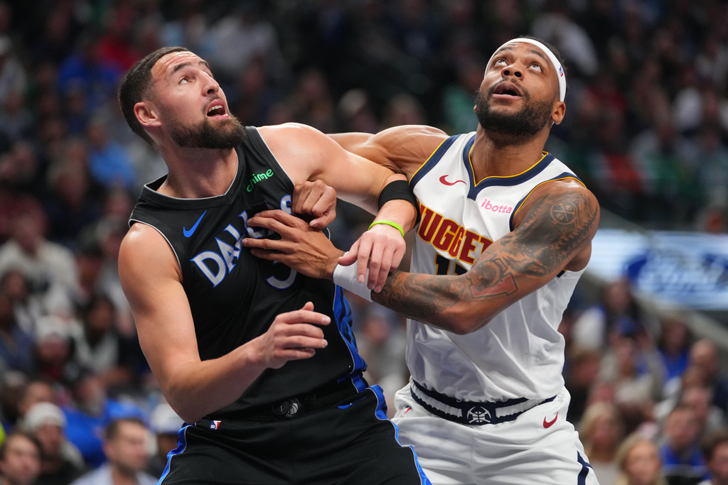 Dallas Mavericks guard Klay Thompson, left, and Denver Nuggets guard Bruce Brown scramble on a free throw by the Nuggets during the first half of an NBA basketball game Wednesday, Jan. 14, 2026, in Dallas. (AP Photo/Julio Cortez)