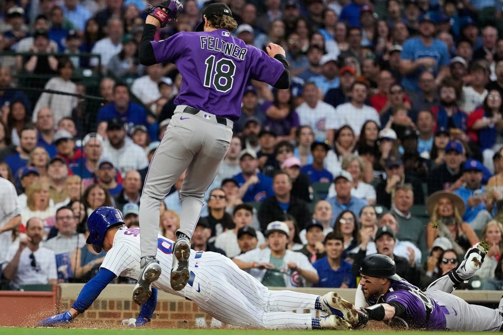 Chicago Cubs' Matt Shaw, bottom left, scores on a wild pitch by Colorado Rockies starting pitcher Ryan Feltner (18) as catcher Brett Sullivan, right, applies a late tag during the second inning of a baseball game in Chicago, Tuesday, June 16, 2026. (AP Photo/Nam Y. Huh)