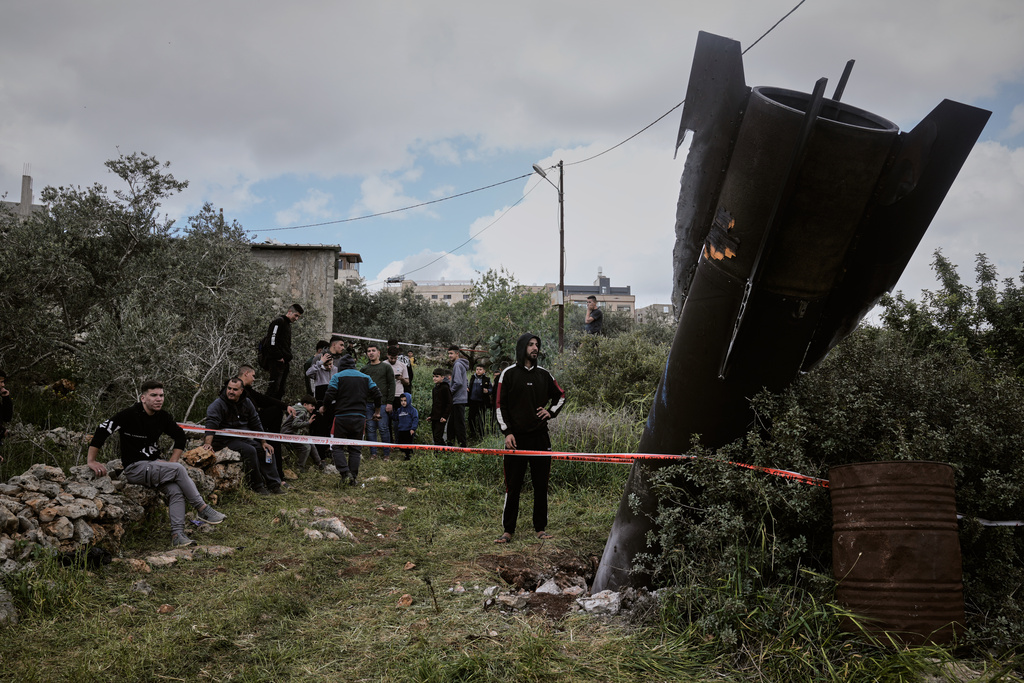 Palestinians gather around the wreckage of an Iranian missile that landed in the West Bank village of Kifl Haris Tuesday, March 24, 2026. (AP Photo/Majdi Mohammed)