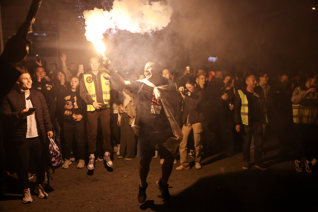 A protestor holds a flare as he welcomes students marching to Novi Sad for a rally on Nov. 1 marking the first anniversary of a train station disaster that killed 16 people, in Indjija, Serbia, Thursday, Oct. 30, 2025. (AP Photo/Armin Durgut)
