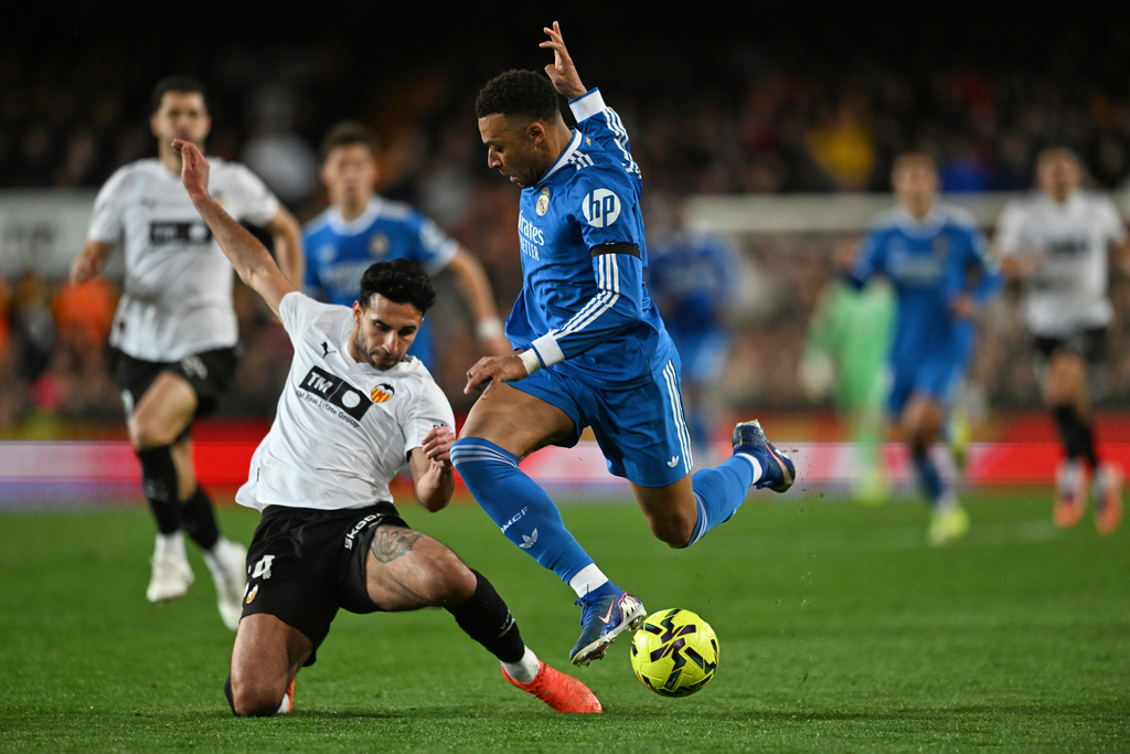 Real Madrid's Kylian Mbappe, centre, and Valencia's Eray Comert challenge for the ball during the Spanish La Liga soccer match between Valencia and Real Madrid in Valencia, Spain, Sunday, Feb. 8, 2026. (AP Photo/Francisco Macia)