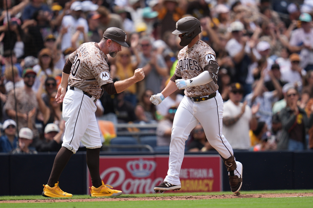 San Diego Padres' Ty France, right, celebrates with third base coach Bob Henley after hitting a home run during the fourth inning of a baseball game against the Colorado Rockies Sunday, April 12, 2026, in San Diego. (AP Photo/Gregory Bull)