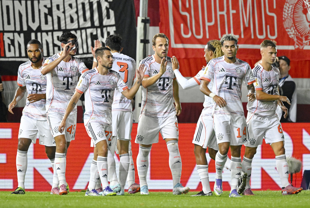Bayern Munich's Harry Kane, center, is congratulated after scoring from the penalty spot against SV Wehen Wiesbaden during the DFB Pokal, Germany Cup, soccer match, Wednesday, Aug 27, 2025, in Wiesbaden, Germany. (Uwe Anspach/dpa via AP)