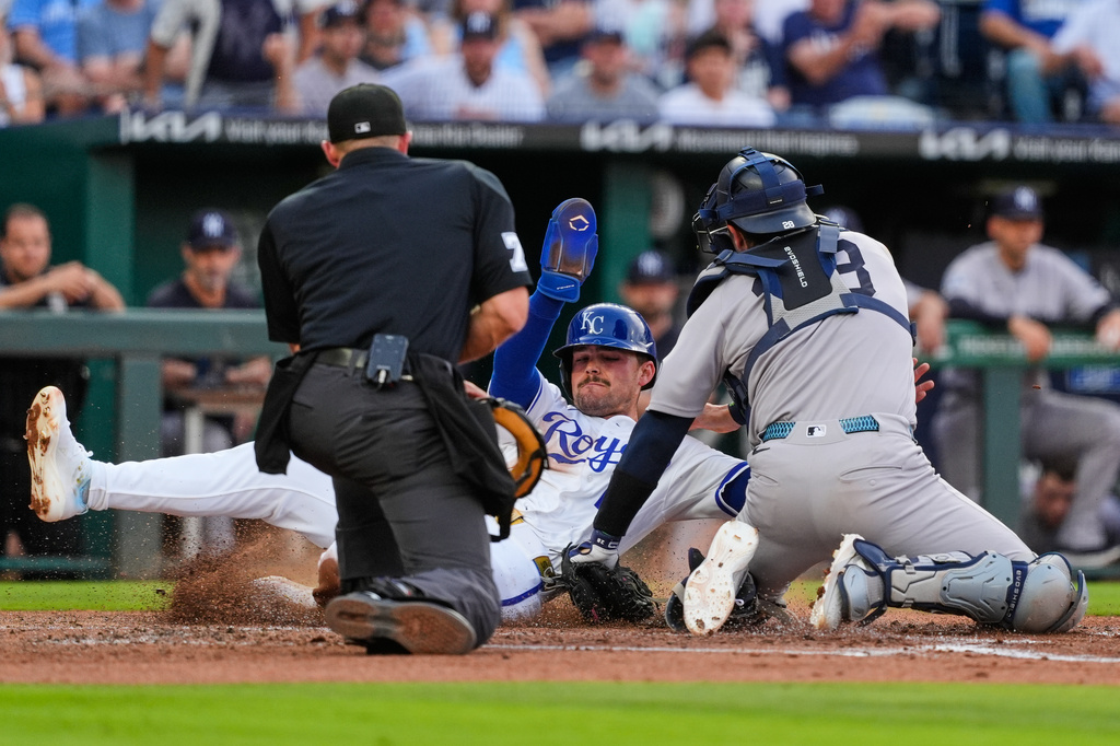 Kansas City Royals' Michael Massey, center, is tagged out at home by New York Yankees catcher Austin Wells as he tried to score on a single by Maikel Garcia during the third inning of baseball game Wednesday, May 27, 2026, in Kansas City, Mo. (AP Photo/Charlie Riedel)