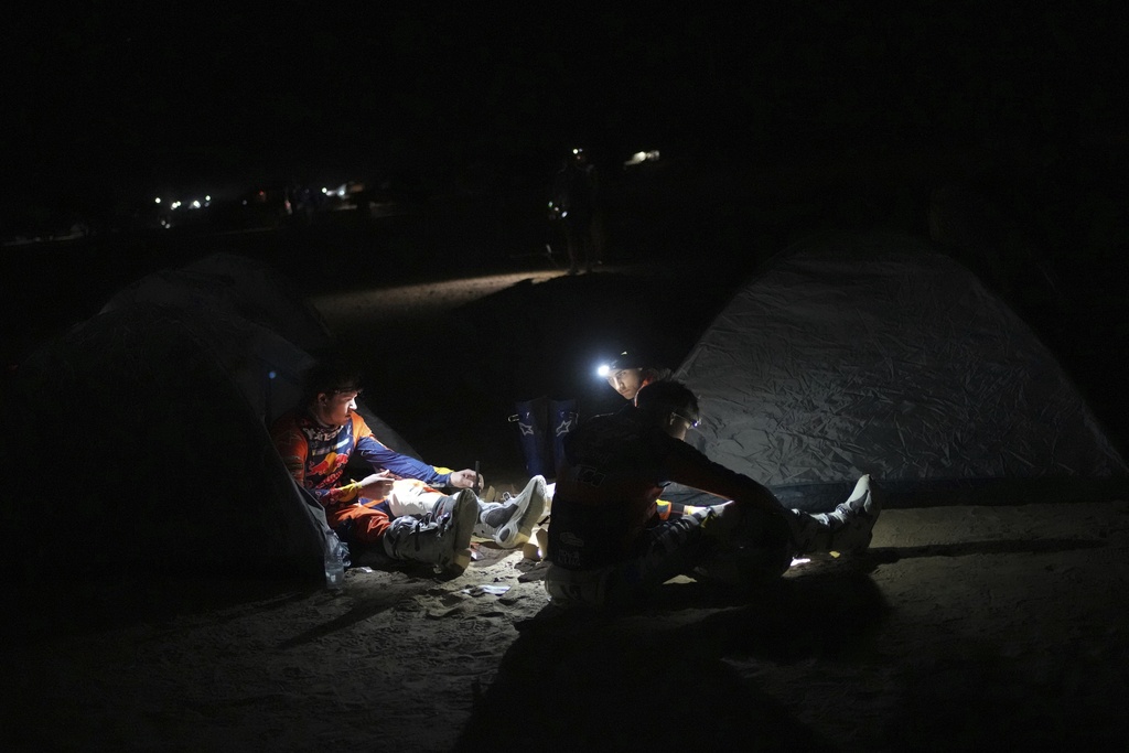 Riders have dinner at the bivouac area after stage two of the Dakar Rally with start in Bisha and finish in Bisha, Saudi Arabia, Sunday, Jan. 5, 2025. (AP Photo/Christophe Ena)