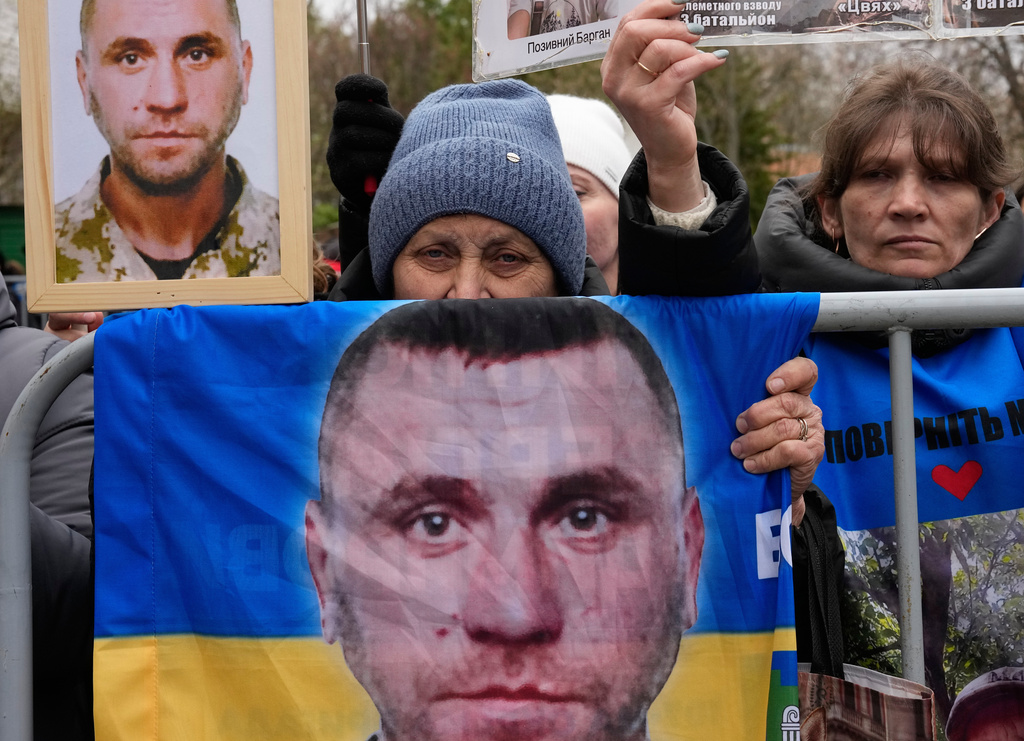 People hold photos of their missed relatives as Ukrainian soldiers return from captivity during a POW exchange between Russia and Ukraine in Chernyhiv region, Ukraine, Saturday, April 11, 2026. (AP Photo/Efrem Lukatsky)