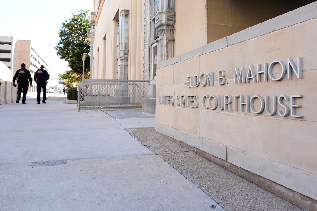 Officers with the Department of Homeland Security walk on the sidewalk outside the Eldon B. Mahon U.S. Courthouse during a trial for nine people connected to a 2025 shooting outside an ICE detention facility, in Fort Worth, Texas, Thursday, March 12, 2026. (AP Photo/Tony Gutierrez)