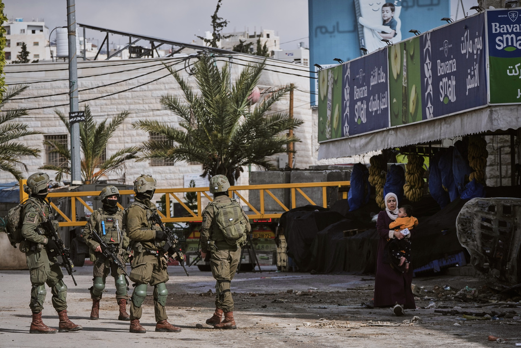 Israeli soldiers take up positions during an army raid in the West Bank city of Hebron Monday, Jan. 19, 2026. (AP Photo/Mahmoud Illean)