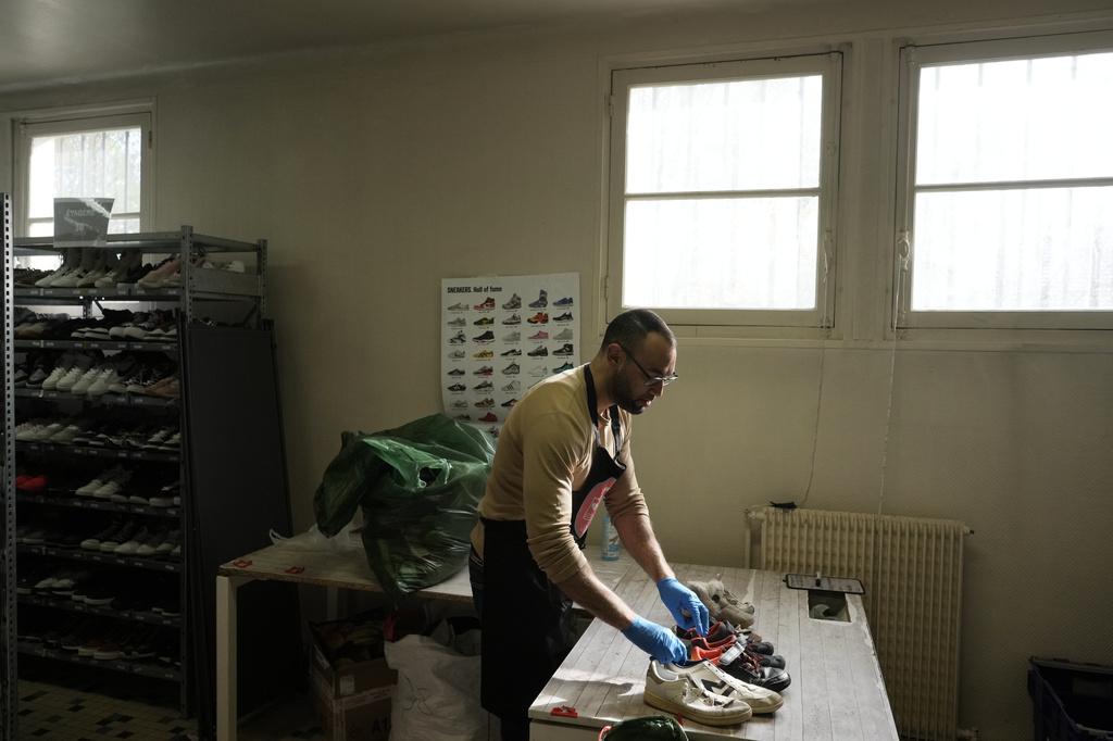 A worker sorts through used sneakers at SneakCoeurZ, a nonprofit organization giving used footwear a second life, in Champs-sur-Marne, east of Paris, Wednesday, March 25, 2026. (AP Photo/Thibault Camus)