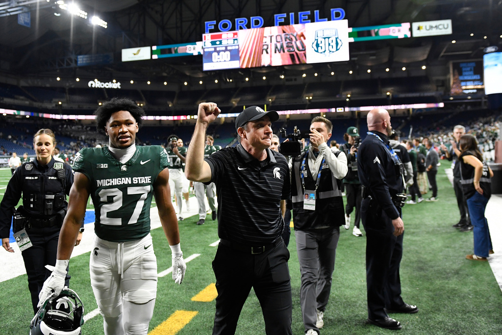 Michigan State head coach Jonathan Smith, center, and Darrin Jones Jr. (27) walk off the field at the end of an NCAA college football game against Maryland, Saturday, Nov. 29, 2025, in Detroit. (AP Photo/Jose Juarez)