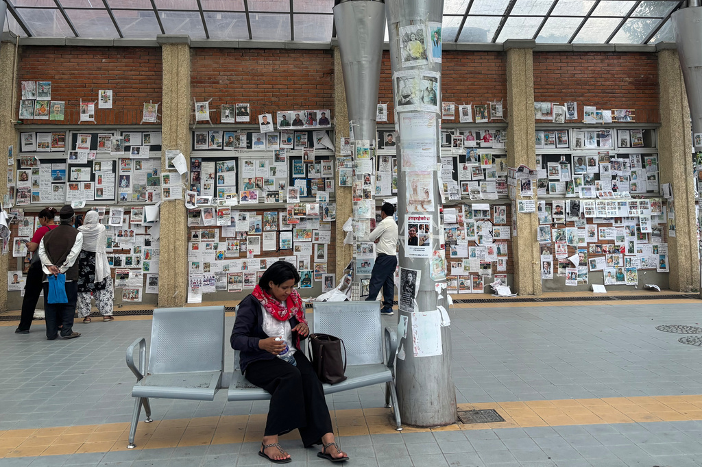 In this photo taken with a smartphone, people look at photographs of hundreds of people missing since last month’s floods, posted on a wall by relatives hoping to receive information about them at Tribhuvan University Teaching Hospital, in Kathmandu, Nepal, Thursday, Sept. 17, 2026. (AP photo/Upendra Man Singh)