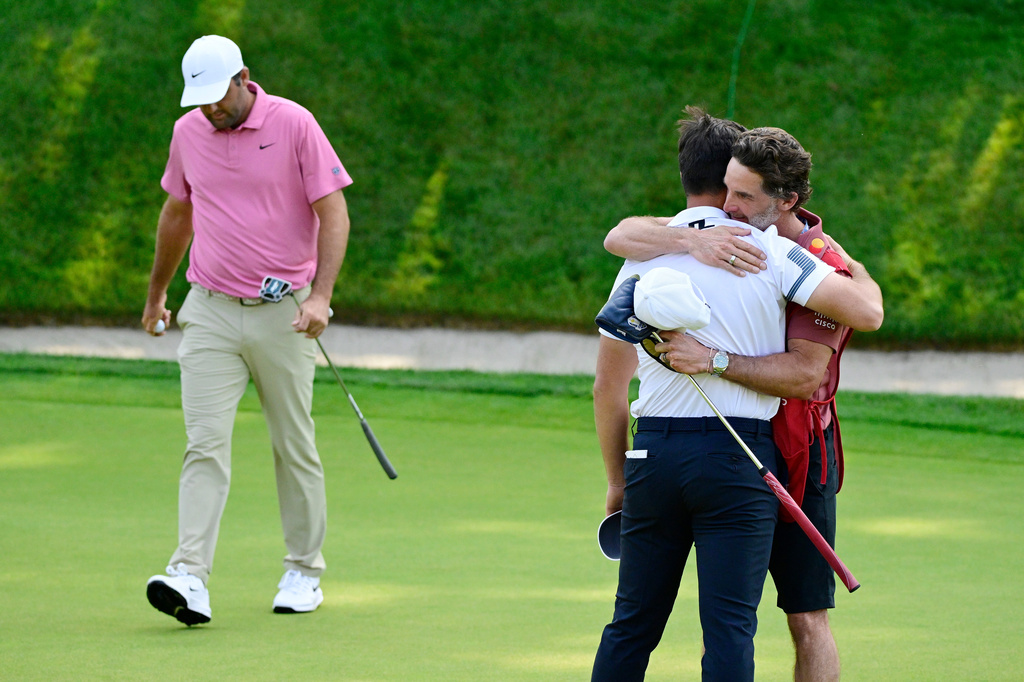 Viktor Hovland, of Norway, right, hugs his caddie Shay Knight as Scottie Scheffler, left, walks off the green on the first playoff hole of the Travelers Championship golf tournament at TPC River Highlands, Monday, June 29, 2026, in Cromwell, Conn. (AP Photo/Jessica Hill)r