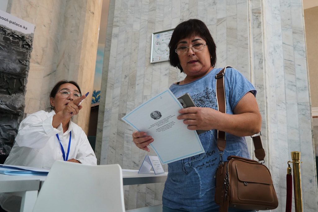 A woman holds her ballot at a polling station during early parliamentary elections in Almaty, Kazakhstan, Sunday, Aug. 23, 2026. (AP Photo/Vladimir Tretyakov)