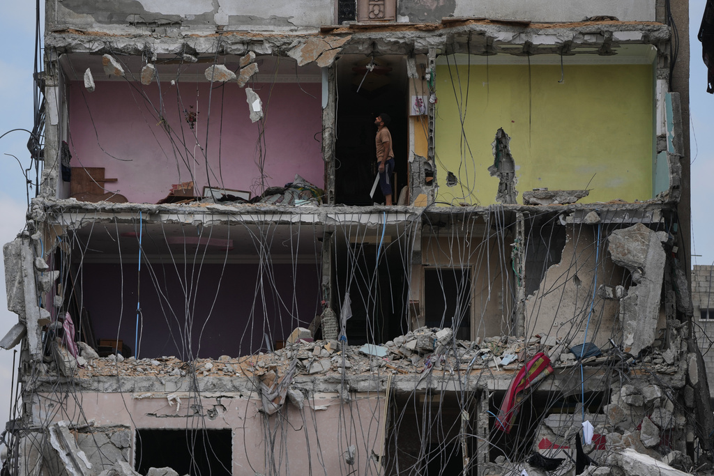 A Palestinian man inspects the remains of a destroyed home in Gaza City, Sunday, Oct. 12, 2025, after Israel and Hamas agreed to a pause in their war and the release of the remaining hostages. (AP Photo/Abdel Kareem Hana)