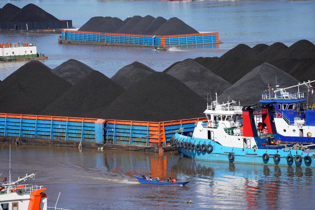 FILE- Boats cruise near barges fully loaded with coal on the Mahakam river in Samarinda, East Kalimantan, Indonesia, on Dec. 19, 2022. (AP Photo/Dita Alangkara, File)