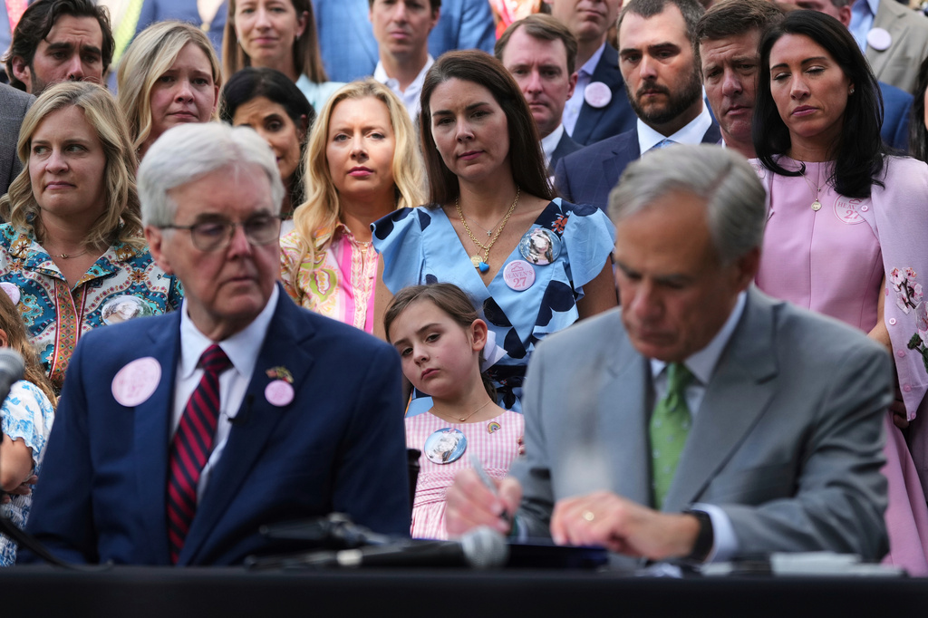 FILE - Emmalynn Lytal, center, sister of Kellyane Lytal, stands with her mother Malorie Lytal, and other family of children who died at Camp Mystic as they watch Texas Gov. Greg Abbott, right, sign camp safety bills into law, Friday, Sept. 5, 2025, in Austin, Texas. (AP Photo/Eric Gay, file)