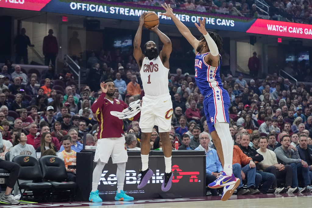 Cleveland Cavaliers guard James Harden (1) shoots as Philadelphia 76ers forward Trendon Watford (12) defends and teammate Donovan Mitchell, left, looks on in the first half of an NBA basketball game in Cleveland, Monday, March 9, 2026. (AP Photo/Sue Ogrocki)