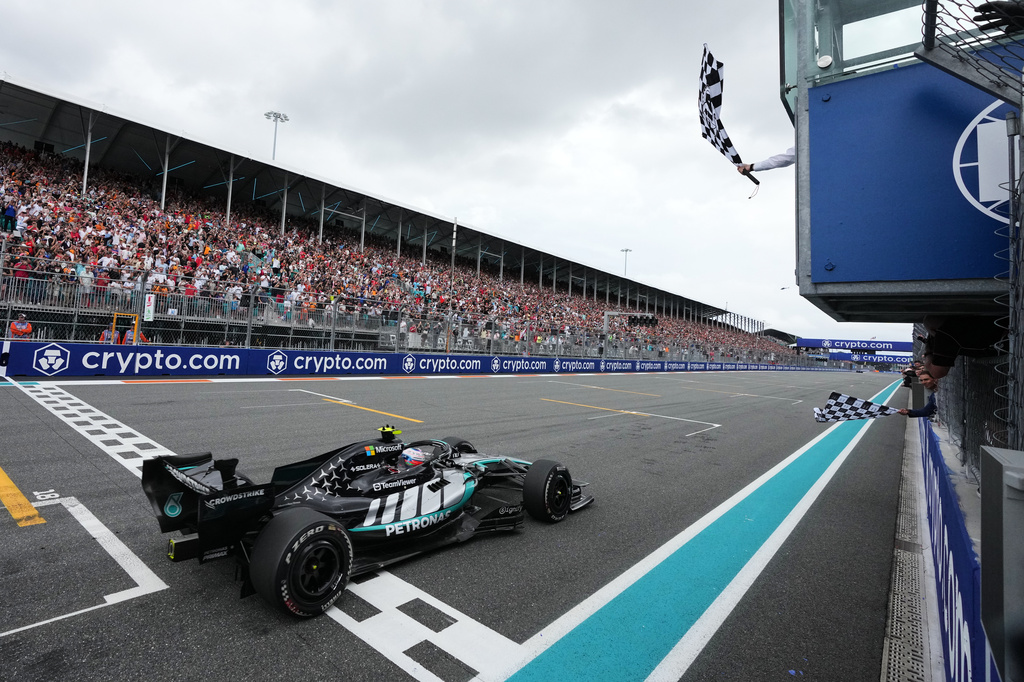 Mercedes driver Kimi Antonelli, of Italy, finishes first in the Miami Formula One Grand Prix auto race as former tennis player Rafael Nadal, bottom right, waves a checkered flag Sunday, May 3, 2026, in Miami Gardens, Fla. (AP Photo/Rebecca Blackwell, Pool) ADDITION: Adds Former tennis player Rafael Nadal, bottom right, waves a checkered flag.