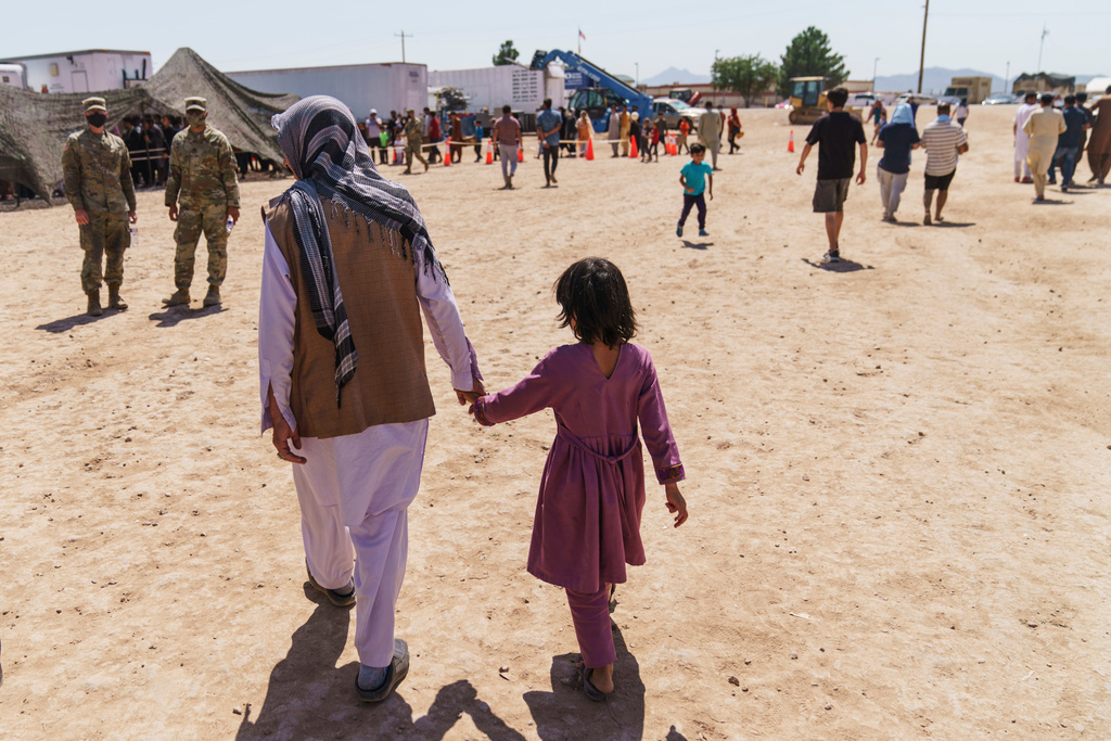 FILE - A man walks with a child through Fort Bliss' Doña Ana Village where Afghan refugees are being housed, in New Mexico, Friday, Sept. 10, 2021. (AP Photo/David Goldman, File)