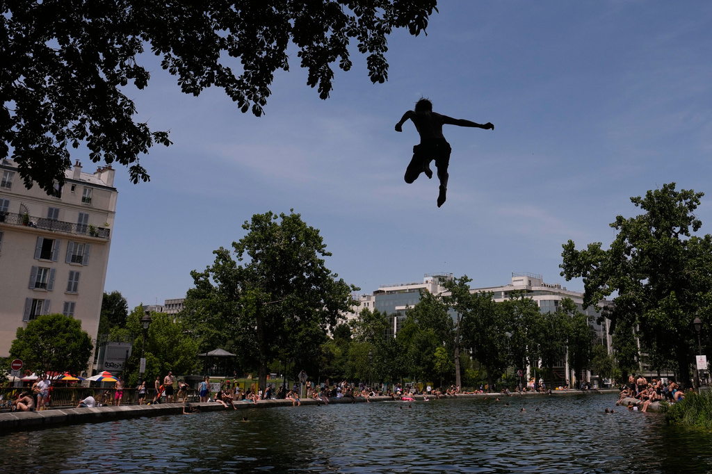 Parisians bath in the Canal Saint-Martin in Paris, as the national weather service, Meteo France, placed 54 departments, about half the country, under a red heat wave alert, Tuesday, June 23, 2026. (AP Photo/Christophe Ena)