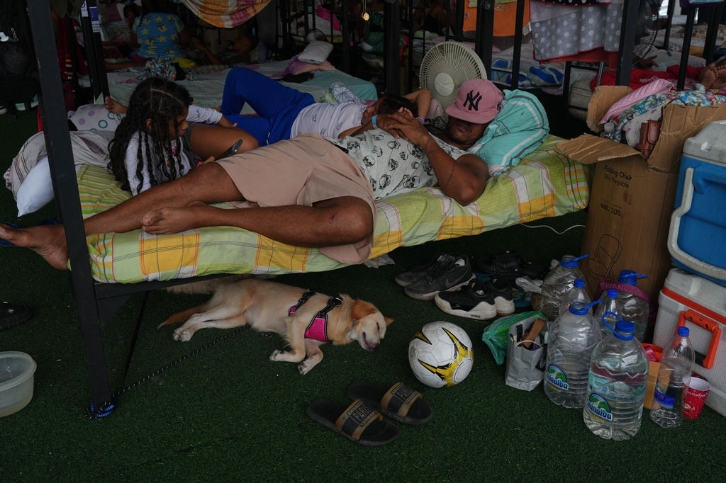 A family rests at a sports center being used as a shelter for those displaced by the earthquakes in La Guaira, Venezuela, Thursday, July 9, 2026. (AP Photo/Ariana Cubillos)