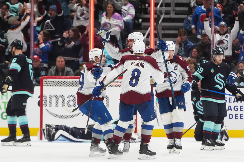 Colorado Avalanche center Brock Nelson, center facing, celebrates his goal with center Nathan MacKinnon, left and defenseman Cale Makar (8) against the Seattle Kraken during the third period of an NHL hockey game Tuesday, Dec. 16, 2025, in Seattle. (AP Photo/Lindsey Wasson)