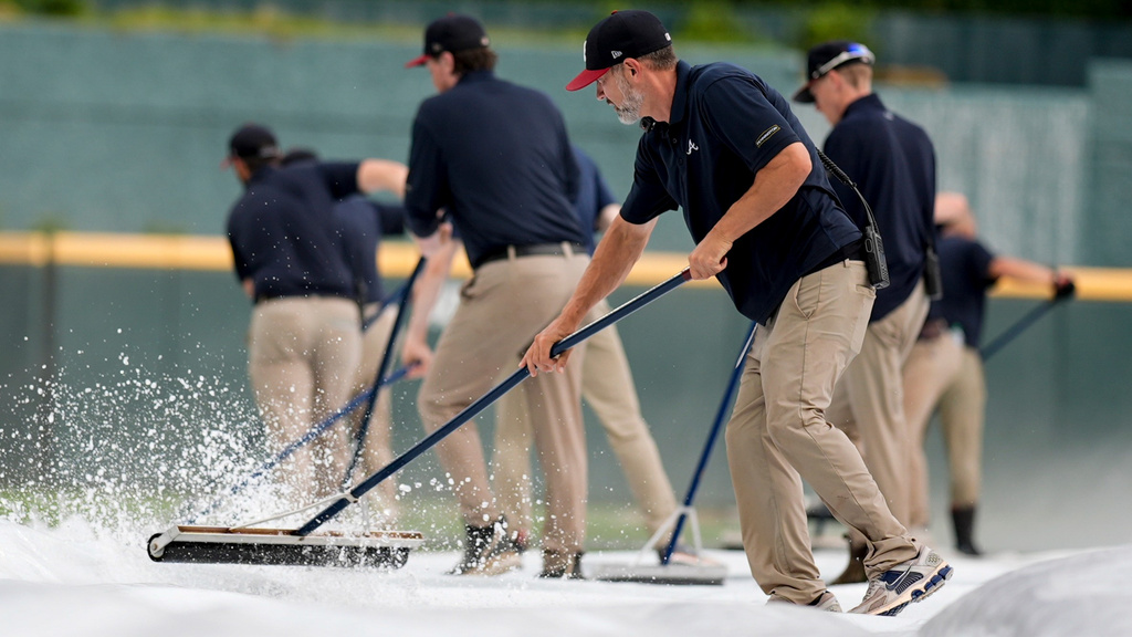 Atlanta Braves grounds crew take water off the tarp covering the field in the sixth inning of a baseball game in rain delay between the Atlanta Braves and the Washington Nationals, Sunday, May 24, 2026, in Atlanta. (AP Photo/Mike Stewart)