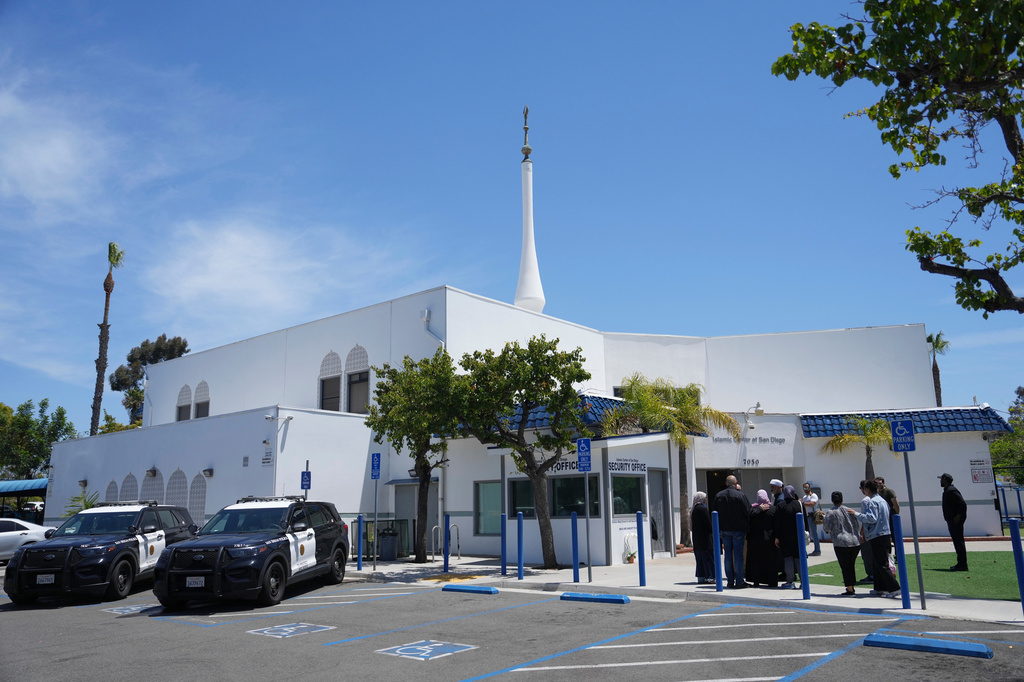 FILE - People gather as police vehicles are parked outside of the Islamic Center of San Diego, the day after a shooting, May 19, 2026, in San Diego. (AP Photo/Jae C. Hong, File)