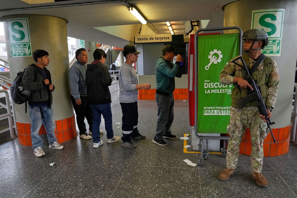 Pedestrians buy bus cards at the bus station as a soldier stands guard in Lima, Peru, Wednesday, Oct. 22, 2025, after President Jose Jeri declared a state of emergency. (AP Photo/Martin Mejia)