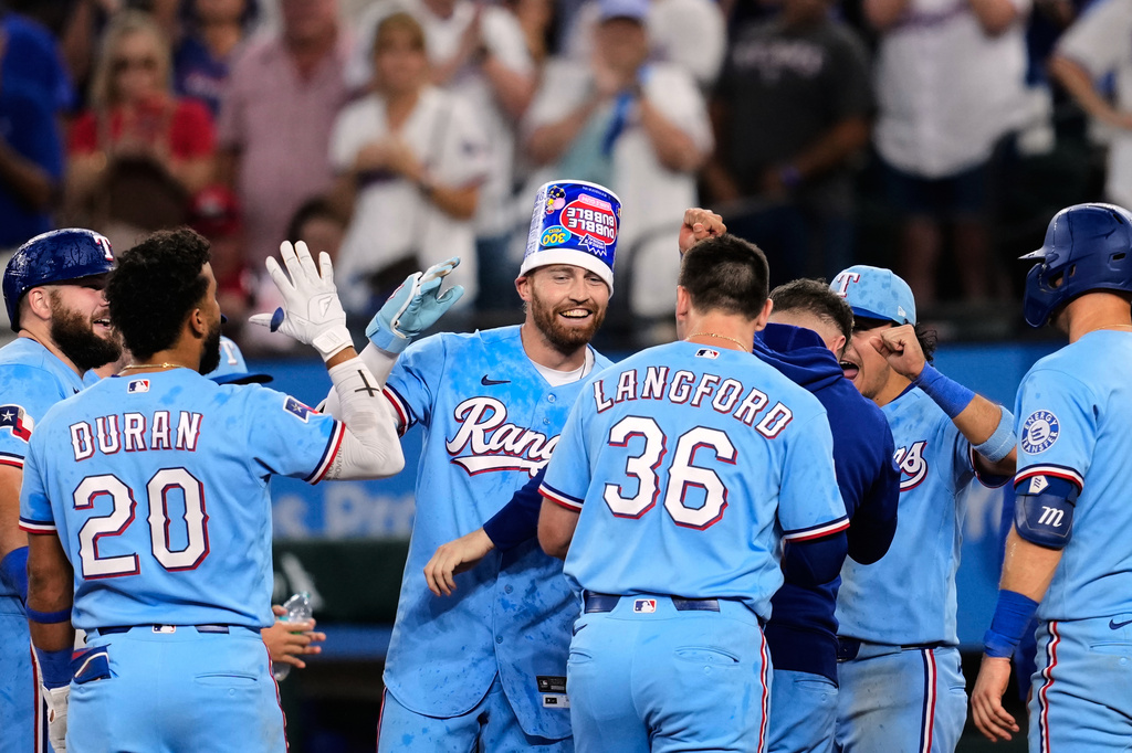 Texas Rangers' Brandon Nimmo, center rear, celebrates with the team after hitting a run-scoring single in the ninth inning of a baseball game against the Houston Astros in Arlington, Texas, Sunday, July 12, 2026. (AP Photo/Tony Gutierrez)