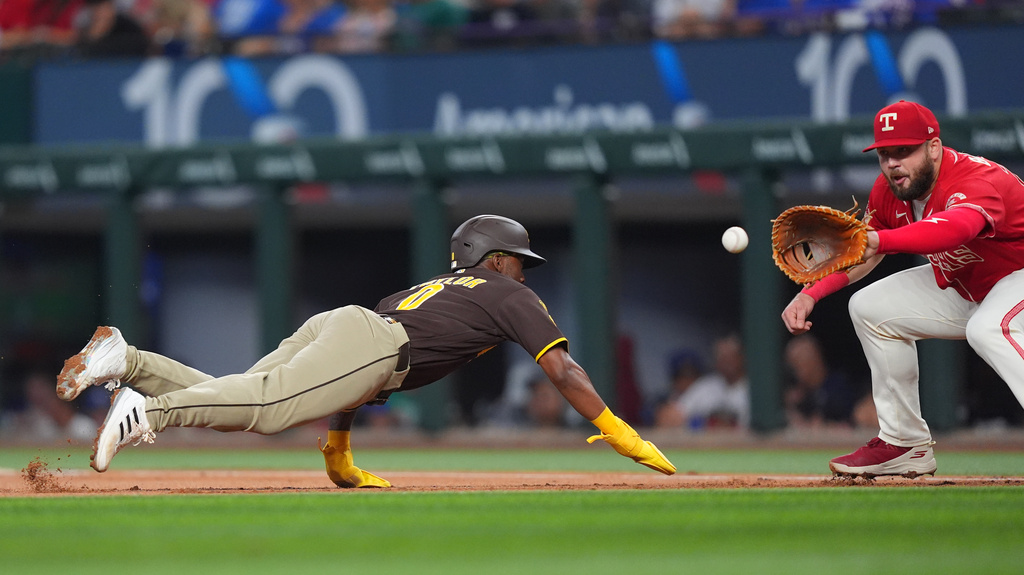 San Diego Padres' Samad Taylor (0) is caught off first base by the pick off throw to Texas Rangers first baseman Jake Burger (21) for the out during the first inning of a baseball game, Saturday, June 20, 2026, in Arlington, Texas. (AP Photo/LM Otero)