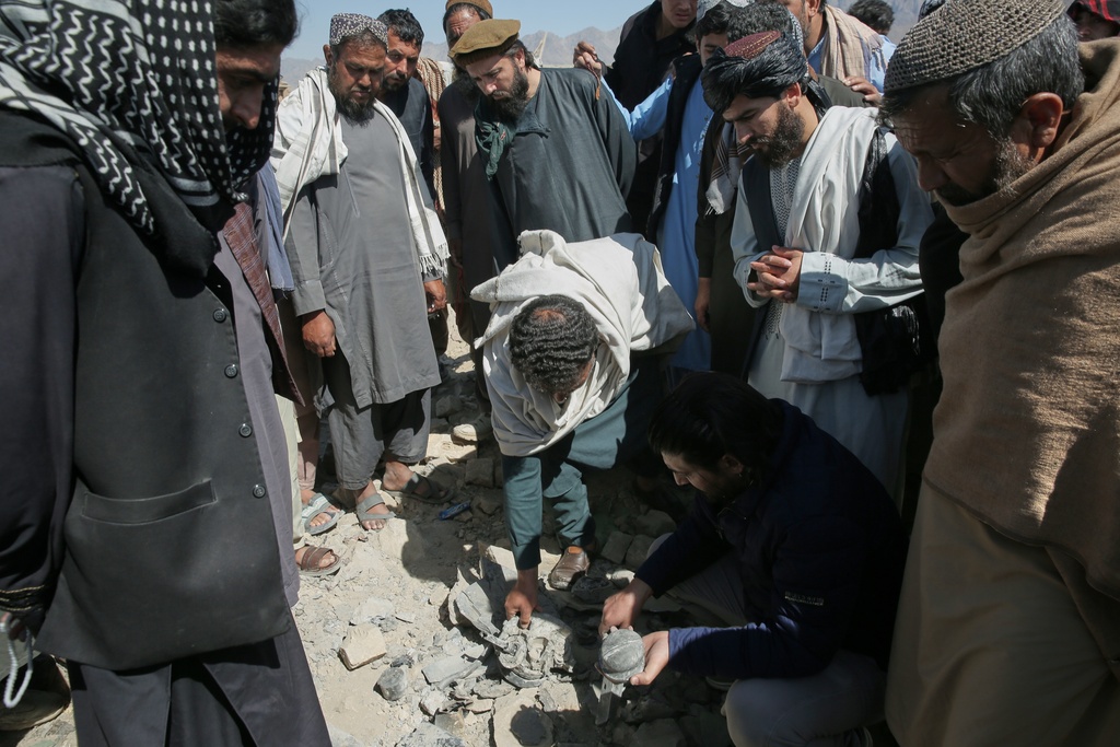 Residents and Taliban police gather the remains of a projectile at the site of a strike in Kabul, Afghanistan, Friday, March 13, 2026. (AP Photo/Barackatullah Popal)