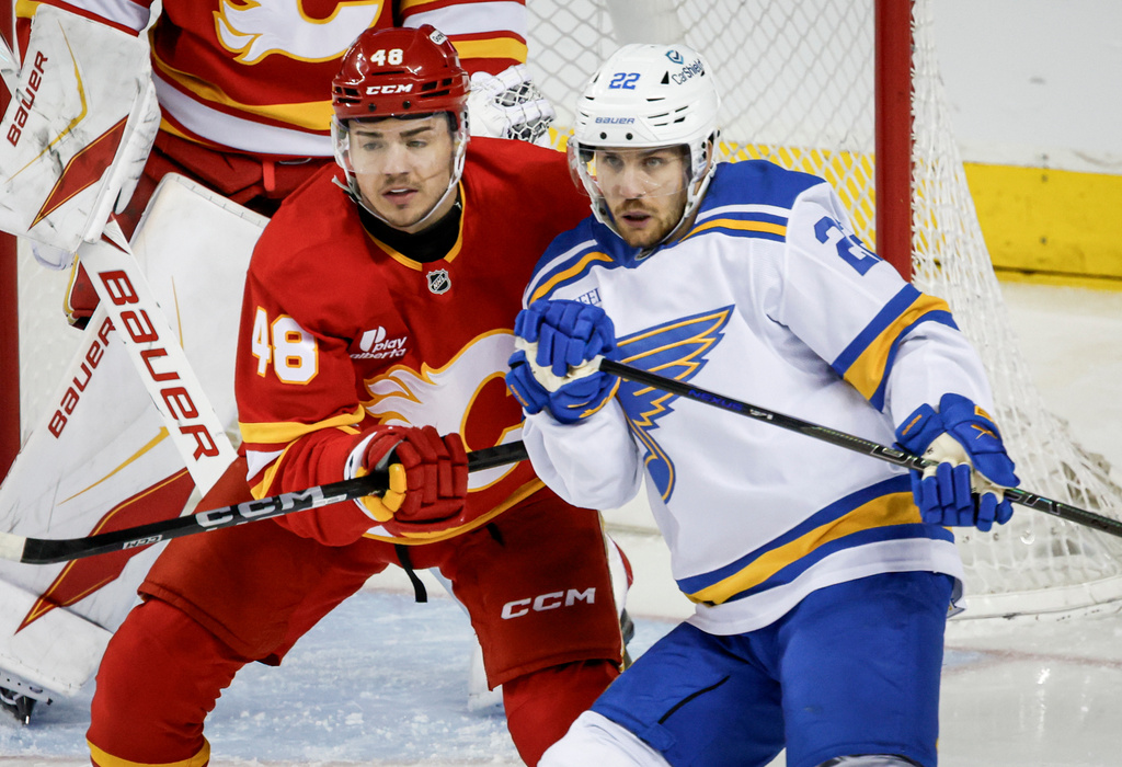 St. Louis Blues' Pius Suter, right, is checked by Calgary Flames' Hunter Brzustewicz during the first period of an NHL hockey game in Calgary on Wednesday, March 18, 2026. (Jeff McIntosh/The Canadian Press via AP)