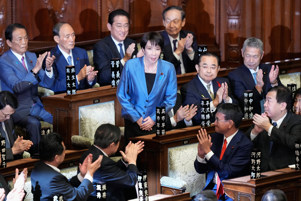 Lawmakers applaud as Sanae Takaichi, standing, was elected as Japan's new prime minister during the extraordinary session of the lower house, in Tokyo, Japan, Tuesday, Oct. 21, 2025.(AP Photo/Eugene Hoshiko)