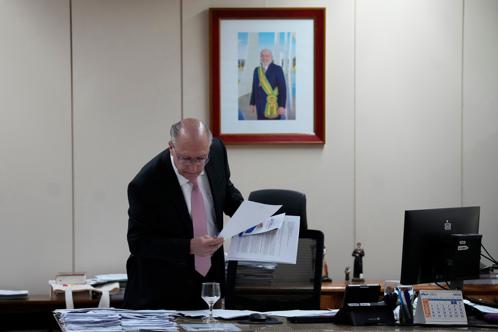 Brazil's Vice President Geraldo Alckmin picks up papers in front of a portrait of Brazil's President Luiz Inacio Lula da Silva before an interview in his office in Brasilia, Brazil, Wednesday, April 22, 2026. (AP Photo/Eraldo Peres)