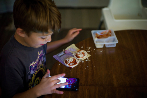Taylor Moyer's oldest son Liam eats a Lunchable while playing with a phone at home, Sunday, Oct. 5, 2025, in Virginia Beach, Va. (AP Photo/John Clark) Taylor Moyer's oldest son Liam eats a Lunchable while playing with a phone at home, Sunday, Oct. 5, 2025, in Virginia Beach, Va. (AP Photo/John Clark)