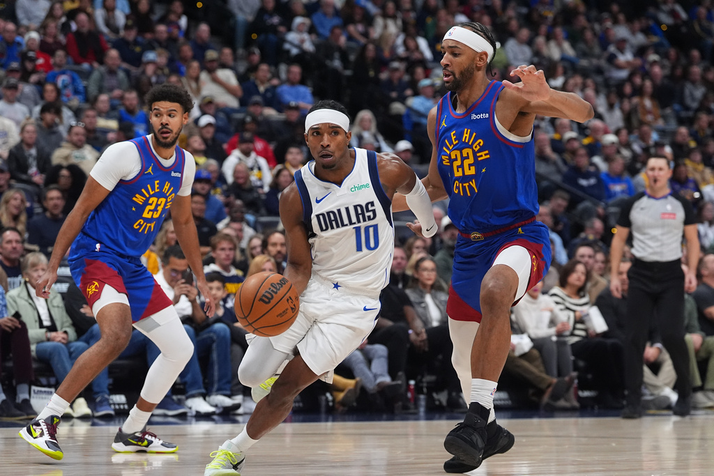 Dallas Mavericks guard Brandon Williams, center, drives between Denver Nuggets forwards Cameron Johnson, left, and Zeke Nnaji in the first half of an NBA basketball game, Monday, Dec. 1, 2025, in Denver. (AP Photo/David Zalubowski)
