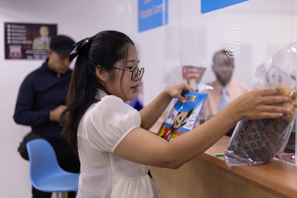 Kanticha Singkhon, 25, picks up the personal belongings of her mother, who died in Sunday's bar fire, at Phahonyothin Police Station in Bangkok, Thailand on Wednesday, July 15, 2026. (AP Photo/Anton L. Delgado)