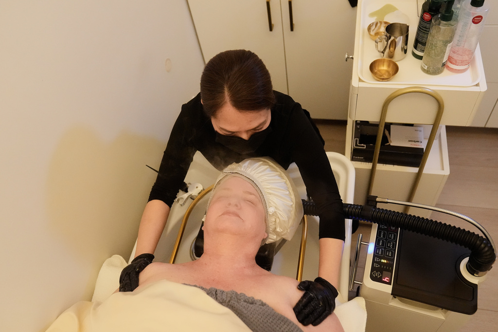 Liz Evans, bottom, wears a warm misting cap, which produces nano mist that hydrates the scalp and hair, as head spa specialist Ha Truong performs a treatment at Sunday Headspa Thursday, April 16, 2026, in San Francisco. (AP Photo/Jeff Chiu)