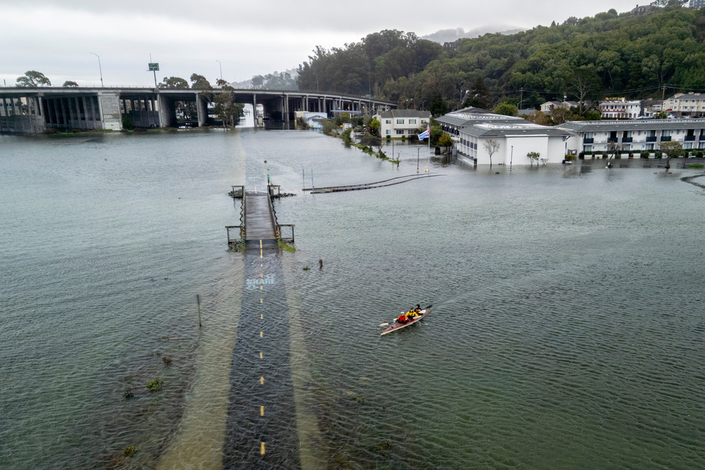 From front, brothers Connor and Brett Cardinal, and friend Eli Ferrell kayak towards a flooded Mill Valley-Sausalito Path during king tide in Mill Valley, Calif., Saturday, Jan. 3, 2026. (Stephen Lam /San Francisco Chronicle via AP)