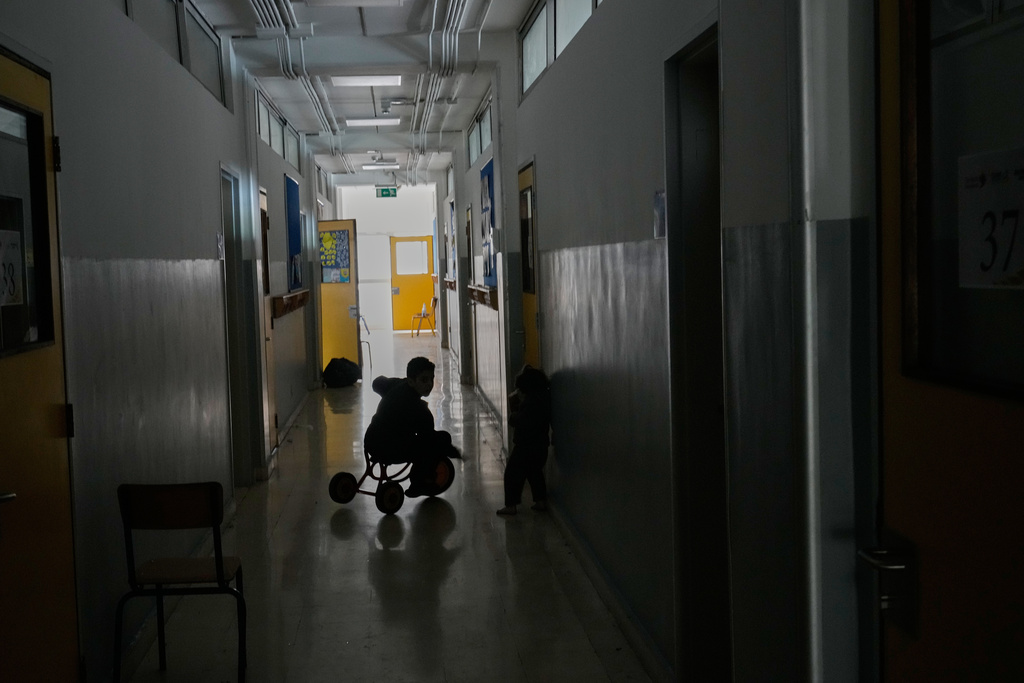 A displaced boy who fled Israeli strikes in southern Lebanon with his family plays on a bicycle in a classroom corridor at a school turned into a shelter in Beirut, Lebanon, Tuesday, March 10, 2026. (AP Photo/Hussein Malla)