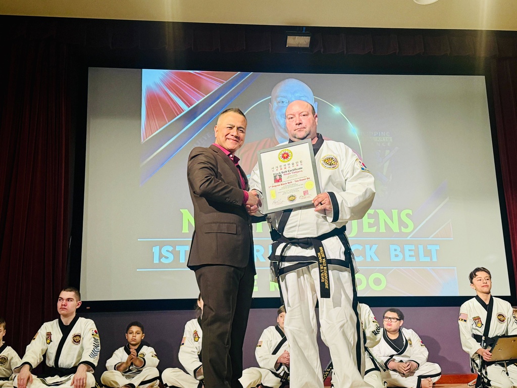 This undated photo provided by Faith Melegrito shows Grand Master Julius Melegrito, left, at a ceremony in Bellevue, Neb., handing Sgt. 1st Class Noah Tietjens, who was killed in a drone strike at a command center in Kuwait, a certificate recognizing him for earning his black belt in Taekwondo. (Faith Melegrito via AP)