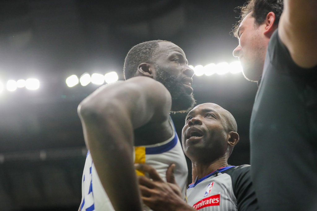 Golden State Warriors forward Draymond Green (23) is held back by referee Courtney Kirkland while talking to New Orleans Pelicans fan Sam Green during the first half of an NBA basketball game against the New Orleans Pelicans in New Orleans, Sunday, Nov. 16, 2025. (David Grunfeld/The Times-Picayune via AP)