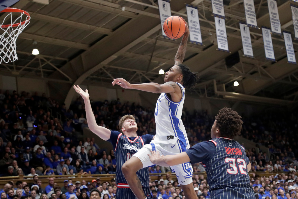 Duke guard Isaiah Evans, center, jumps in for a dunk against Howard center Danas Kazakevicius, left, and forward Travelle Bryson (32) during the second half of an NCAA college basketball game Sunday, Nov. 23, 2025, in Durham, N.C. (AP Photo/Chris Seward)